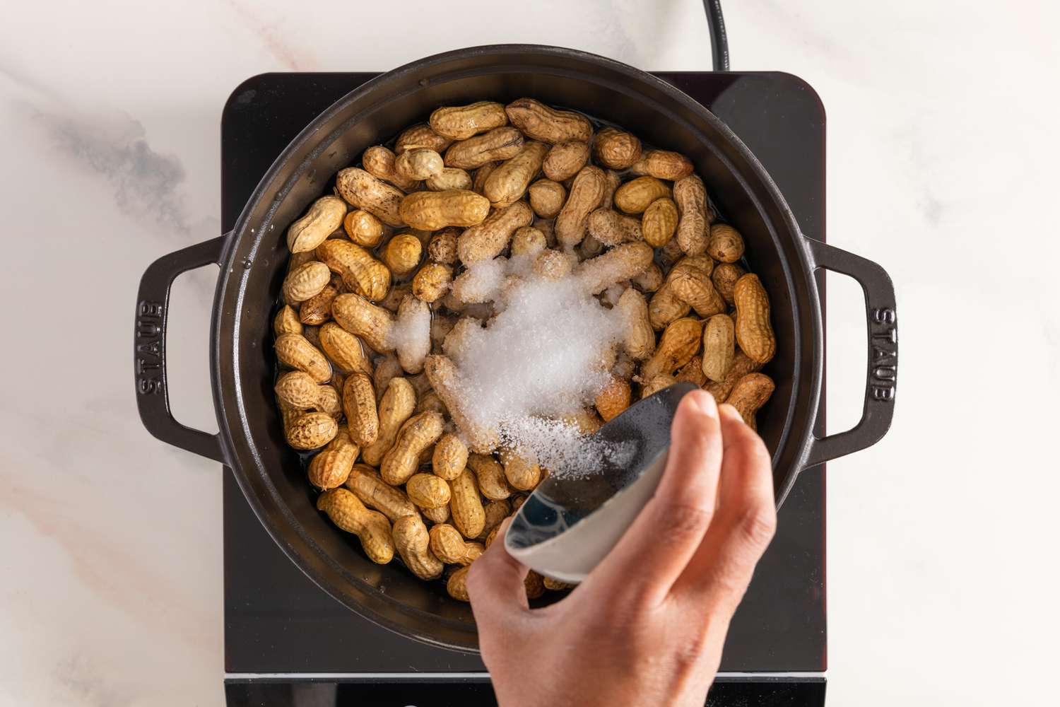 Adding salt to a pot of raw in-shell peanuts
