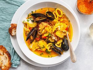 Overhead view of a bowl of bouillabaise and sliced bread.