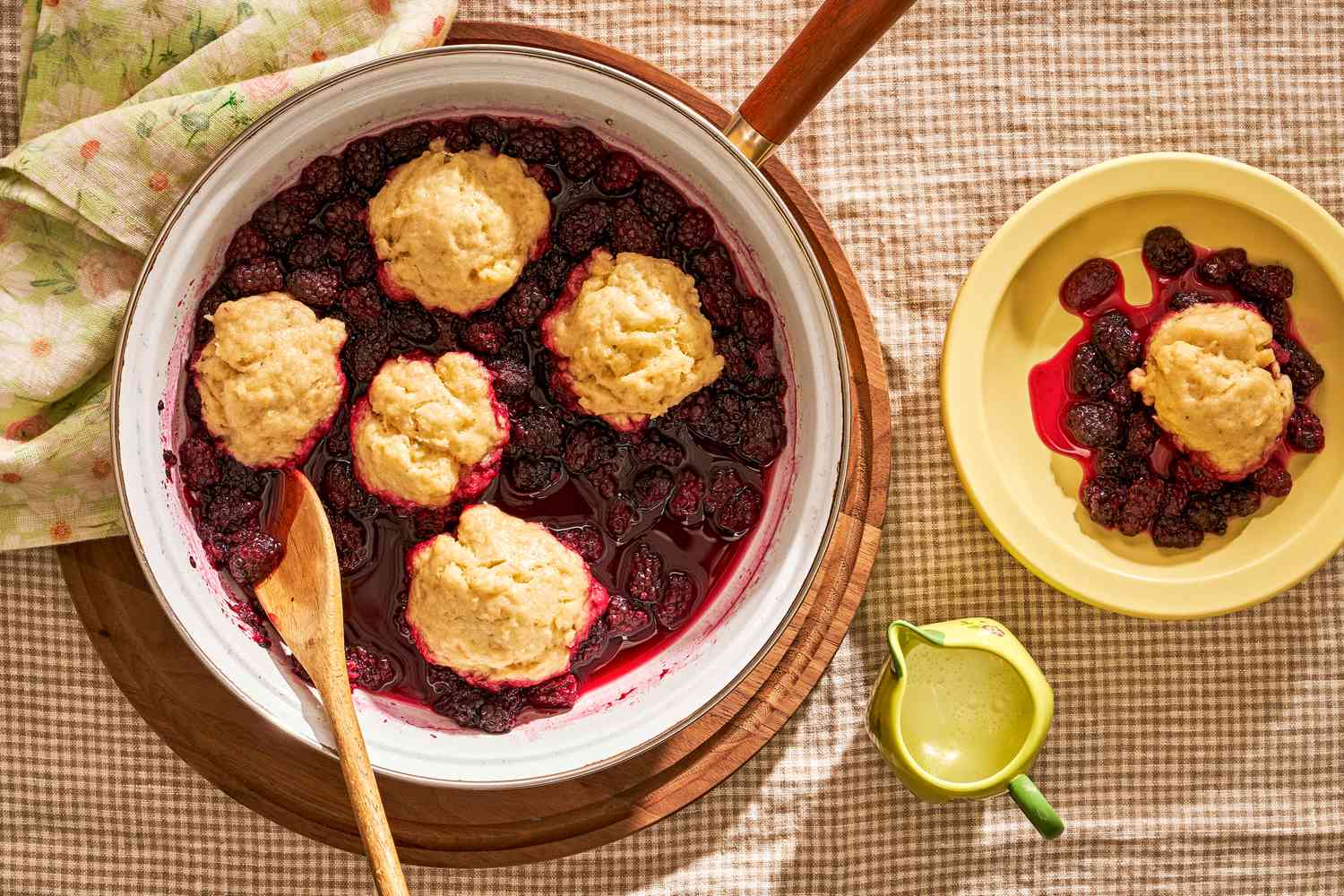 Blackberry Slump in a pot with a wooden spoon and serving in a bowl on the side