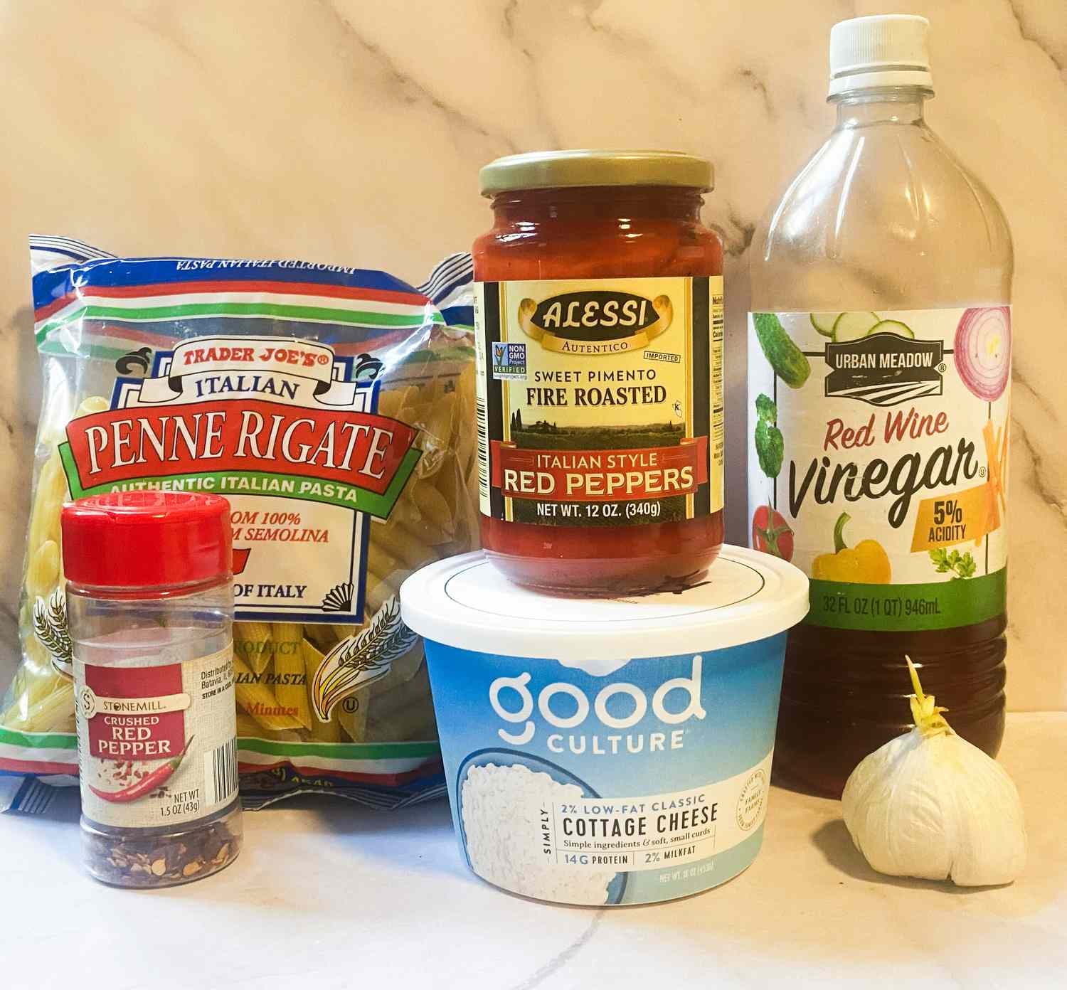 Ingredients for a pasta dish including penne pasta roasted red peppers red wine vinegar cottage cheese red pepper flakes and garlic