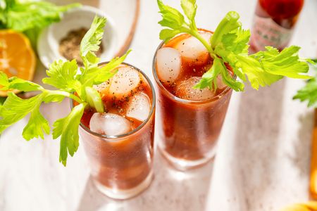 Two glasses of Bloody Mary cocktails with celery garnish on a table