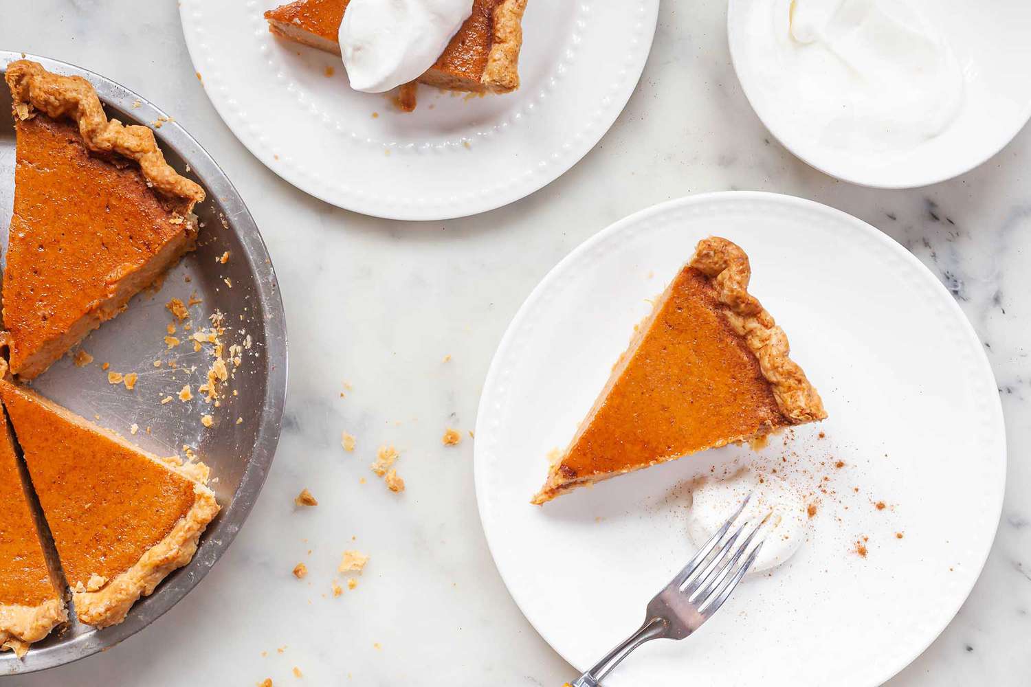 A couple of slices of classic sweet potato pie with the pie off to the side and some whipped cream