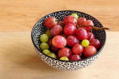 A bowl with red and green grapes