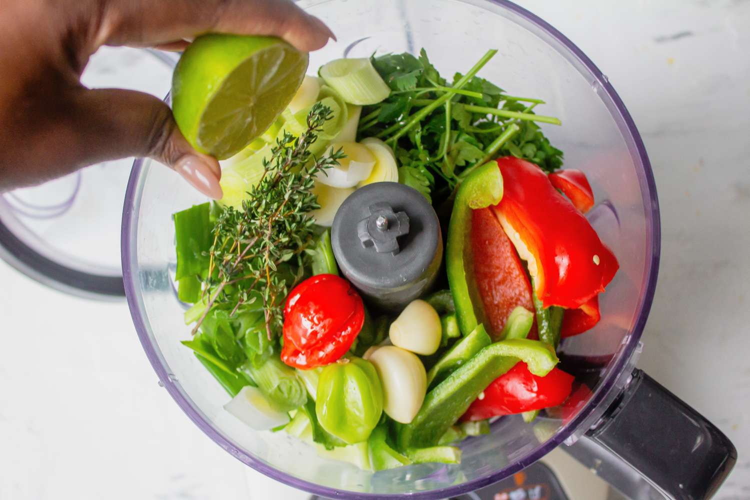Lime juice added to onion, bell peppers, celery, and leeks in food processor for Haitian epis recipe