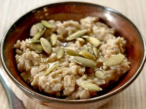 A bowl of oatmeal topped with pumpkin seeds on a wooden table
