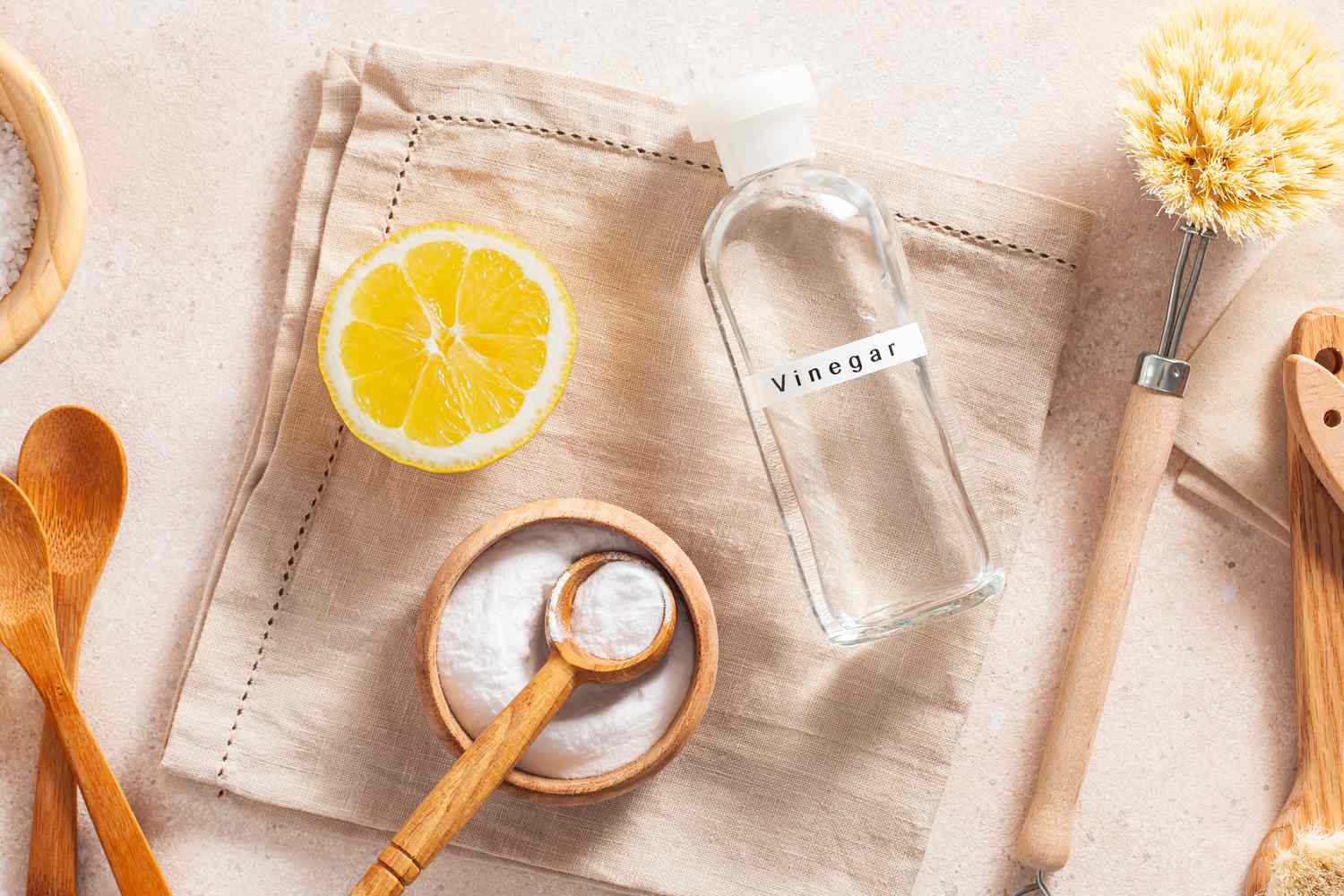homemade cleaning supplies ingredients (half of a lemon, baking soda, and a bottle of vinegar)