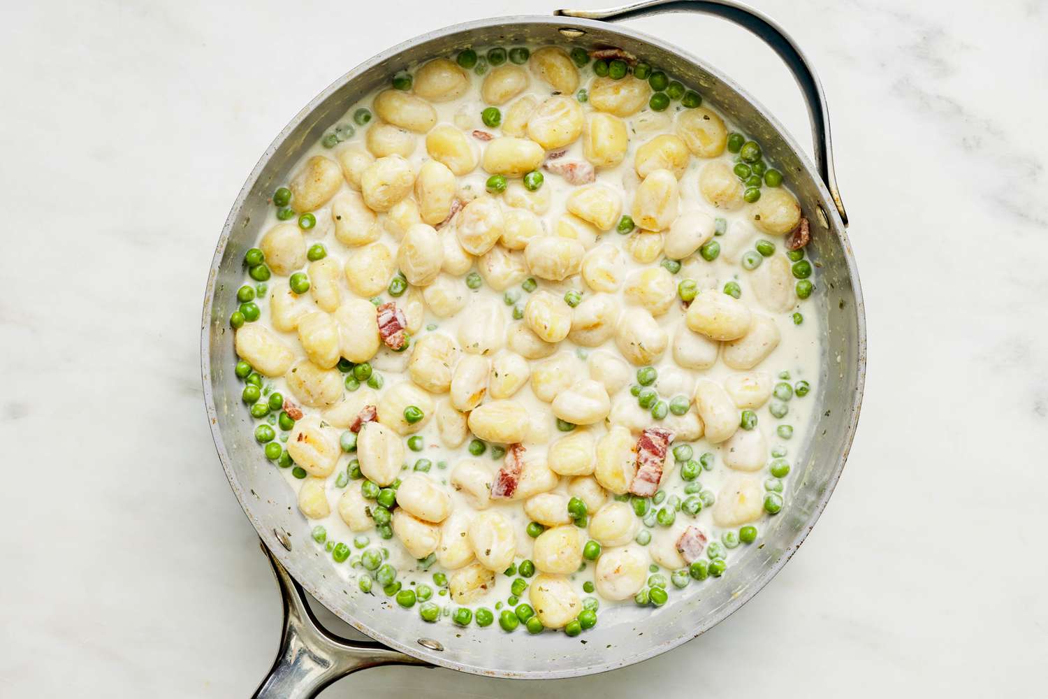 Creamy Gnocchi With Bacon and Peas in a skillet