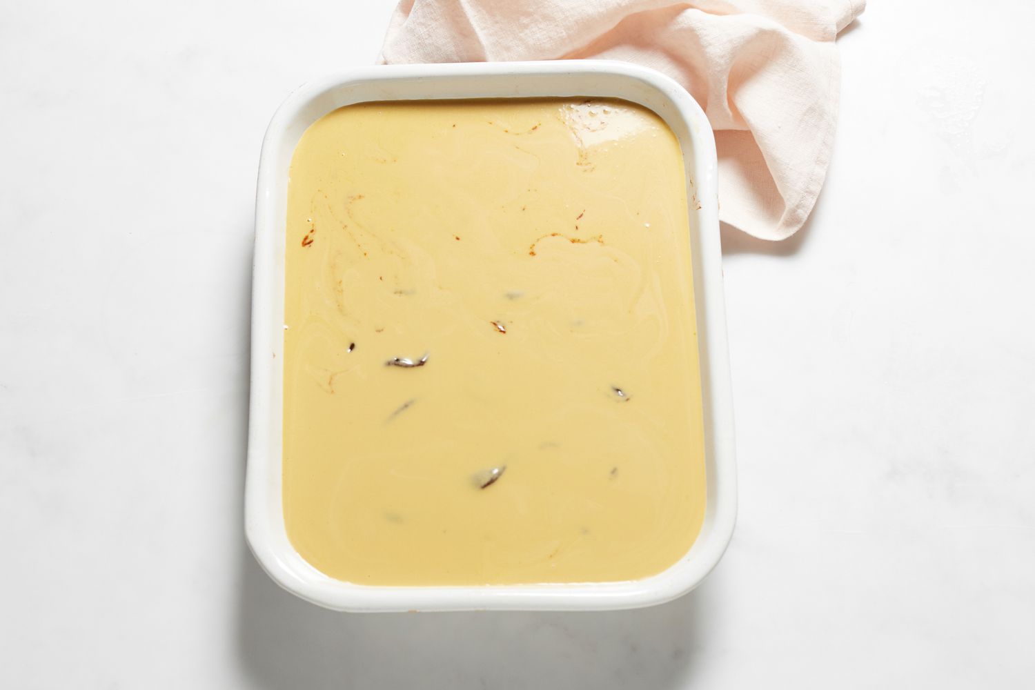 Pouring batter and spreading bean paste on a Sticky rice cake with red bean paste in a baking dish.