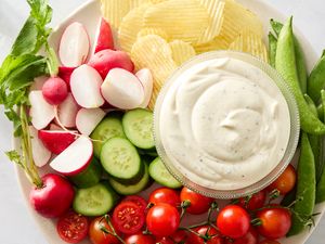 A plate of vegetables chips and a bowl of creamy dip