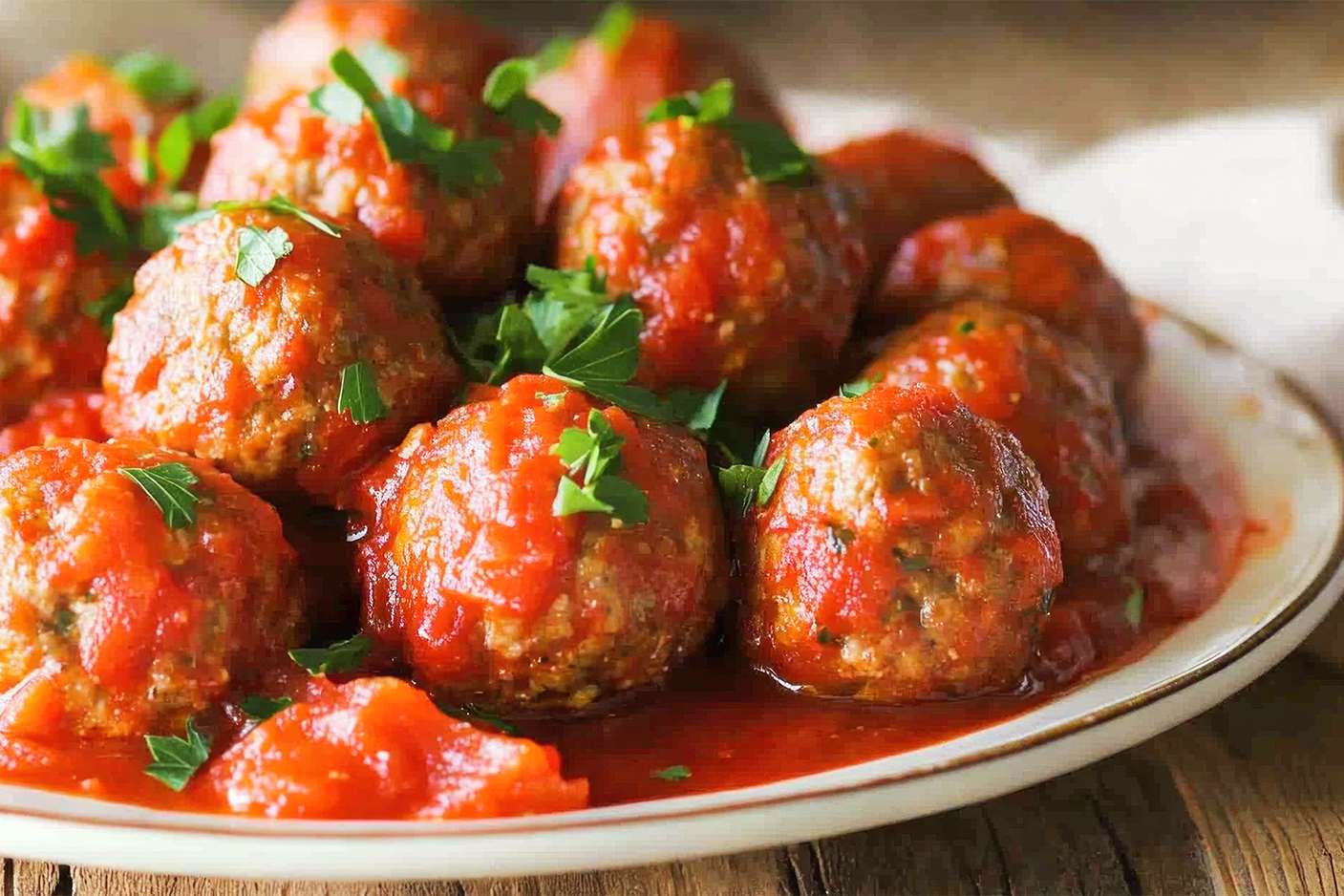 Plate of meatballs with tomato sauce and herb garnish