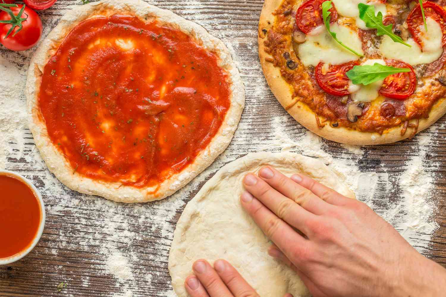 someone forming pizza dough on a counter next to a pizza topped with tomato sauce and a baked pizza 