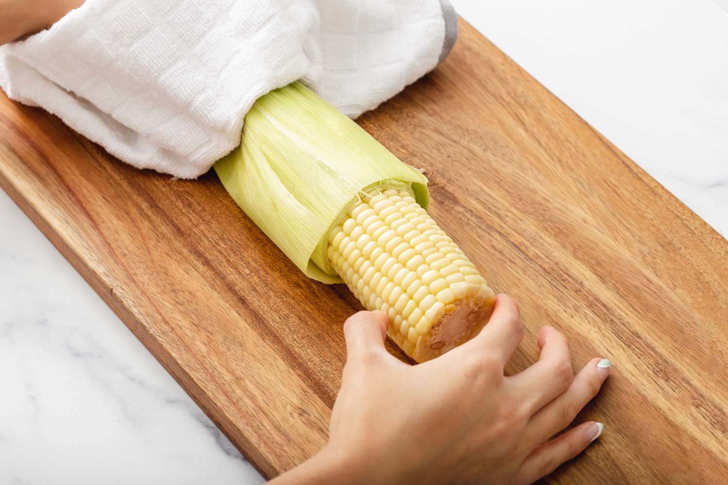 Sliding the corn out of the husk to show how to make corn on the cob.