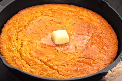Cornbread in cast iron skillet with dollop of melting butter on top of the cornbread 