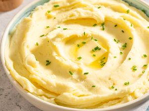 Bowl of mashed potatoes topped with butter and chives