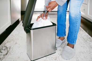 A person pulling a trash bag out of a trash can