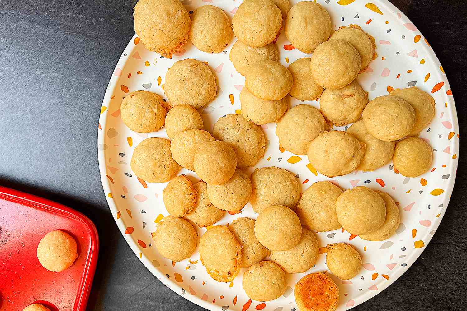 Retro cookies on a white serving plate with sprinkles of color, with one cookie flipped over to show browned bottom