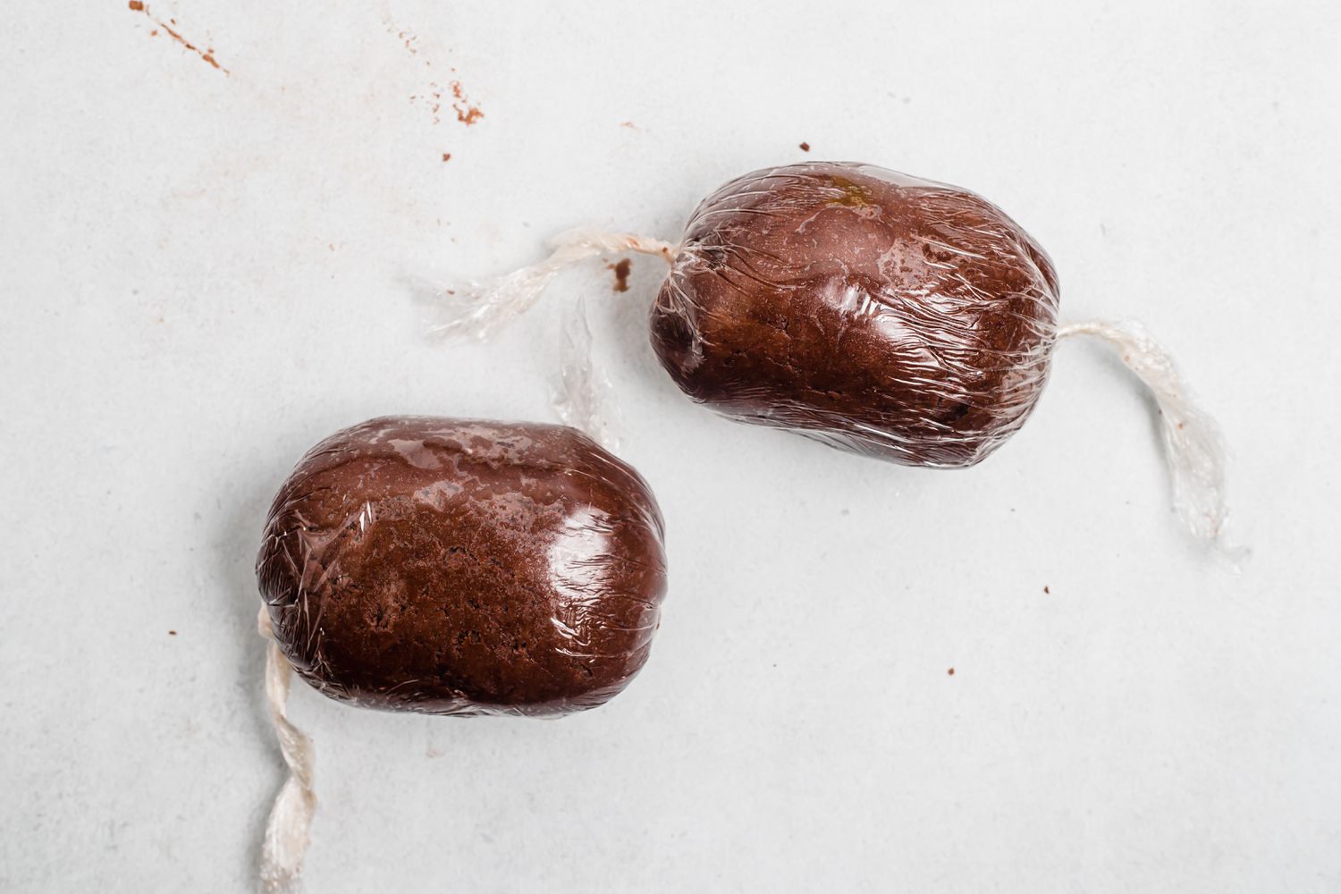 Two rolls of dough wrapped in plastic wrap to make easy shortbread with chocolate and crushed peppermint.