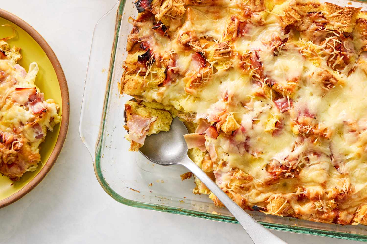 A baked casserole dish of croque monsieur breakfast casserole featuring layers of toasted bread ham and melted cheese