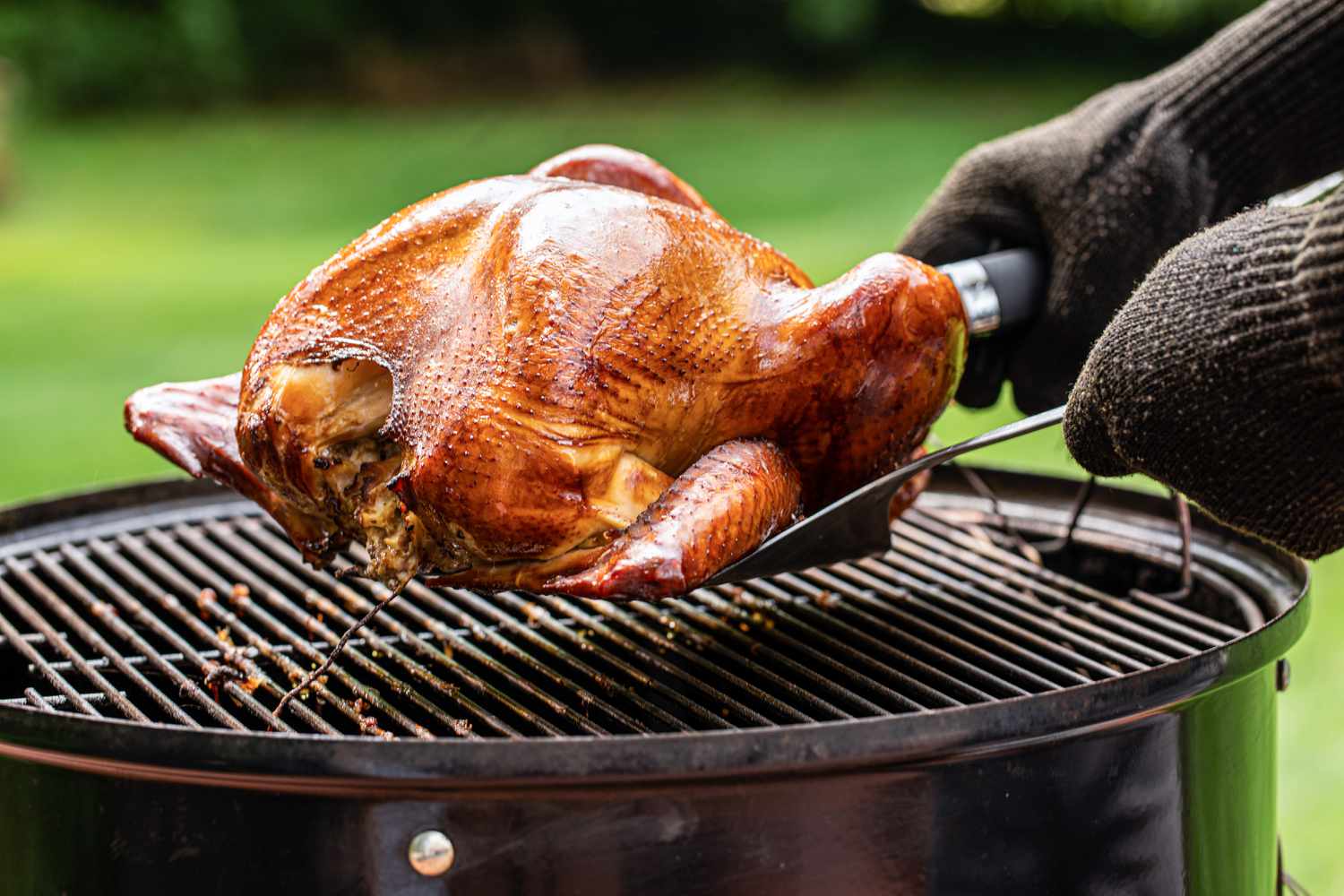 Removing a citrus-brined smoked turkey from the grill.