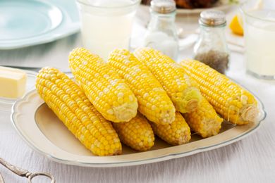 Plate of cooked corn on the cob on a table set for dining