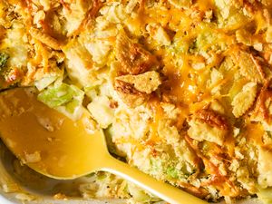 A serving of baked cabbage casserole with cheese and crispy toppings a yellow serving spoon in the dish