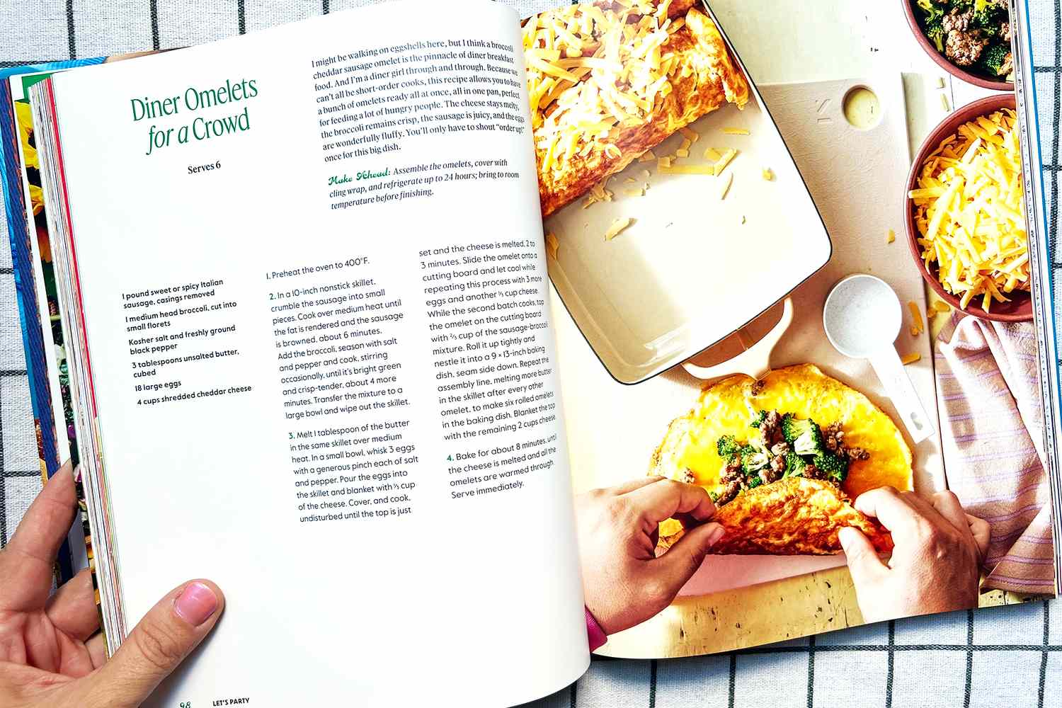 Someones hands folding an omelet filled with vegetables on an open cookbook page