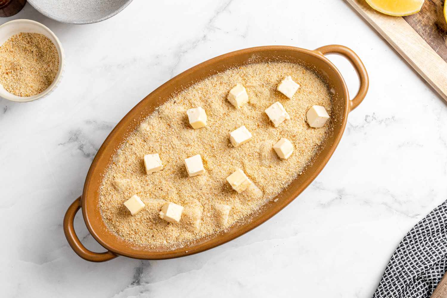 Scallops in a baking dish topped with breadcrumbs, ready to go into the oven