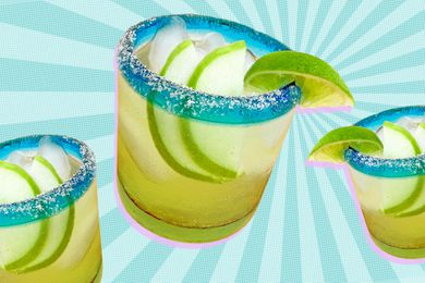 Three glasses of 3-Ingredient Sparkling Apple Margarita with slices of apple inside and salt and lime on the rim against a speckled blue background