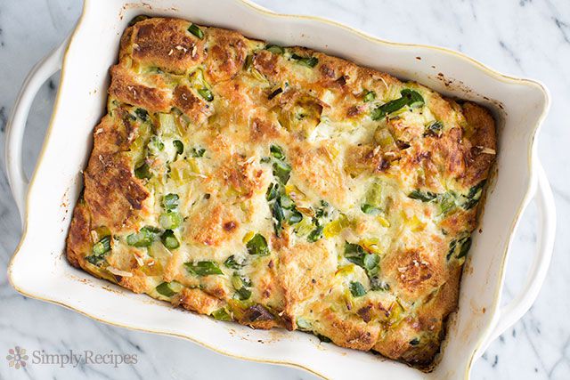 A breakfast casserole with leeks and asparagus in a white baking dish