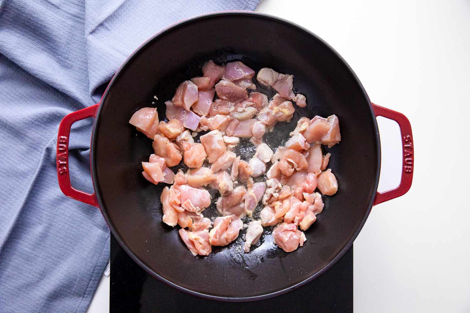 Chicken Cooking in a Wok on a Portable Burner, and Next to It, a Blue Kitchen Towel for Chop Suey Recipe
