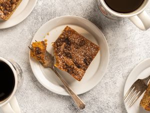 Slices of coffee cake served on small plates with forks alongside cups of coffee