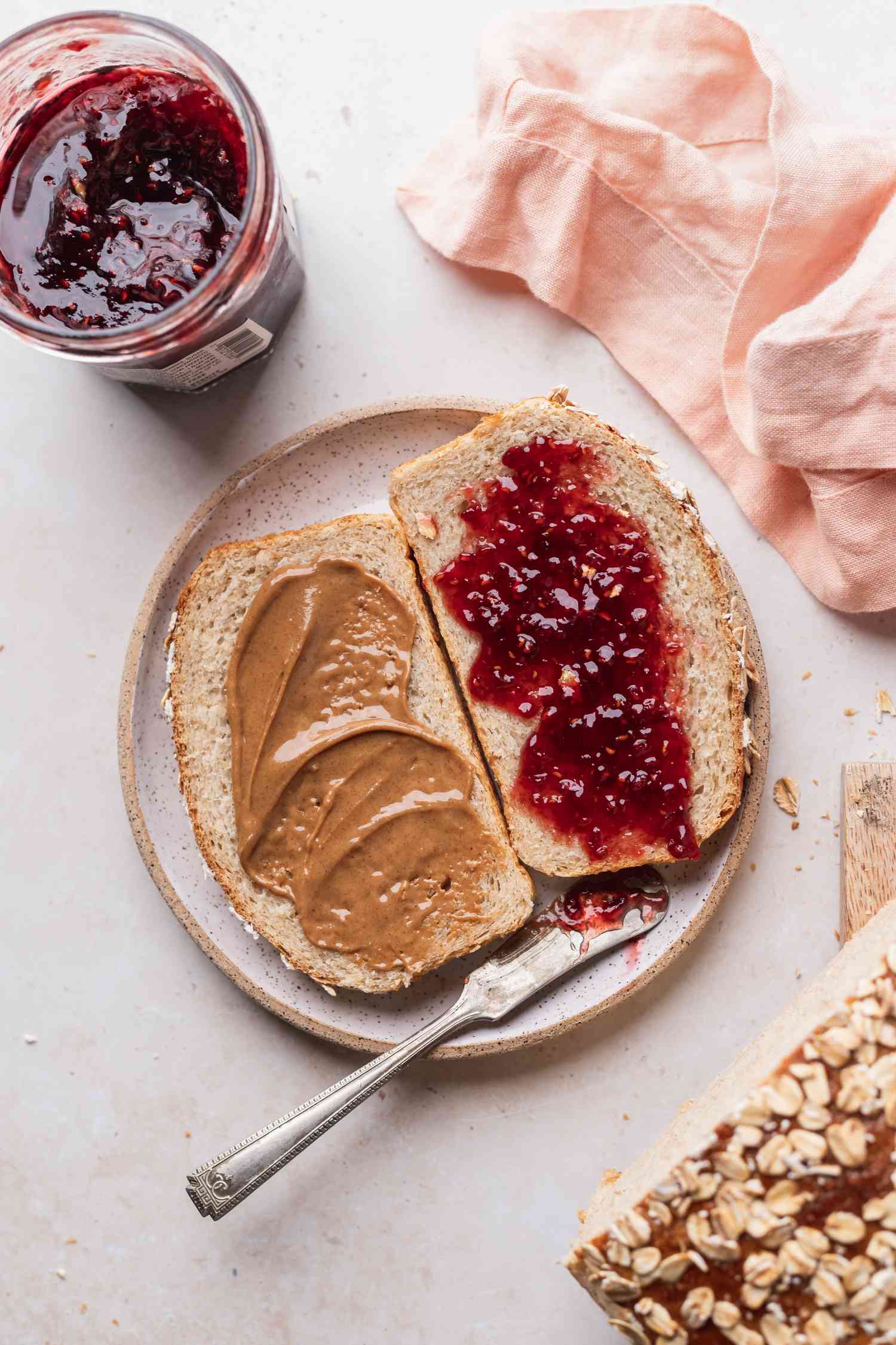 Overhead view of homemade oat bread slices spread with peanut butter and jelly on a plate