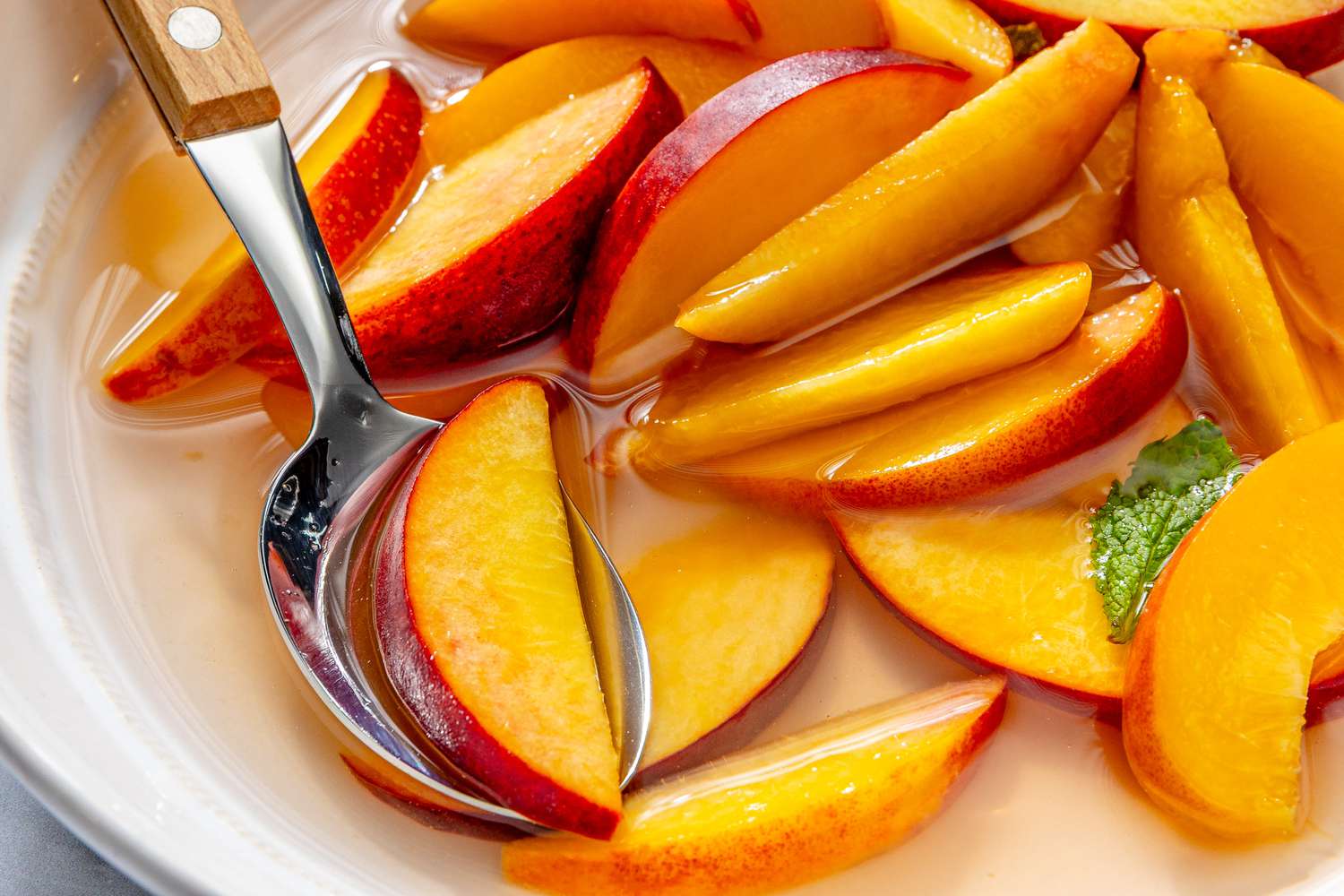 Sliced peaches in liquid being served with a spoon