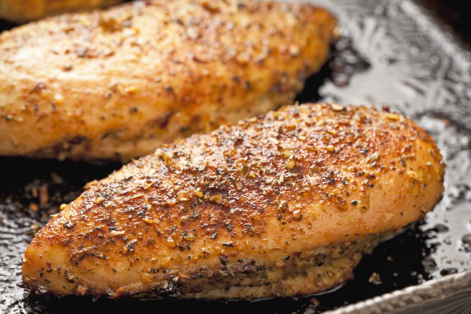 Cooked and seasoned chicken breast on a baking tray