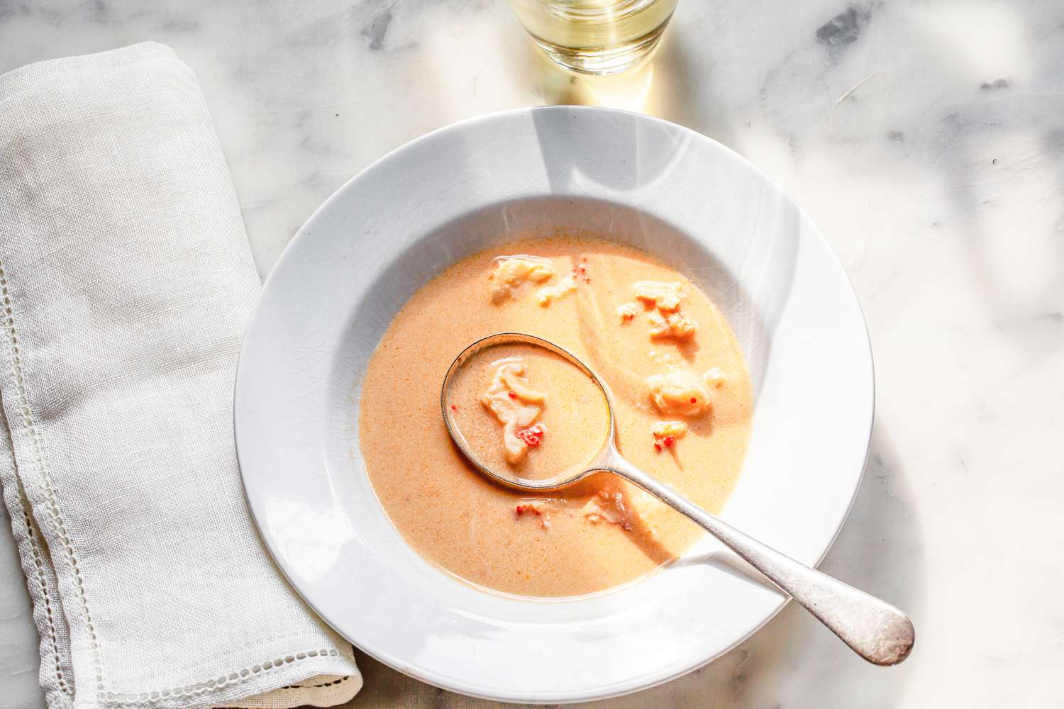 Bowl of Lobster Bisque Next to a Table Napkin and a Glass
