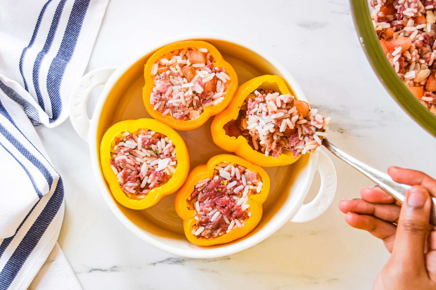 Filling bell peppers with beef and rice stuffing.