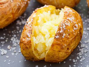 Closeup side view of a baked potato sprinkled with coarse salt