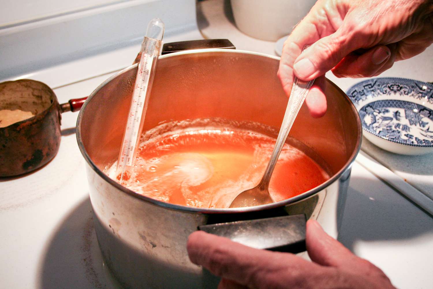 Skimming foam from a pot of cooking quince jelly