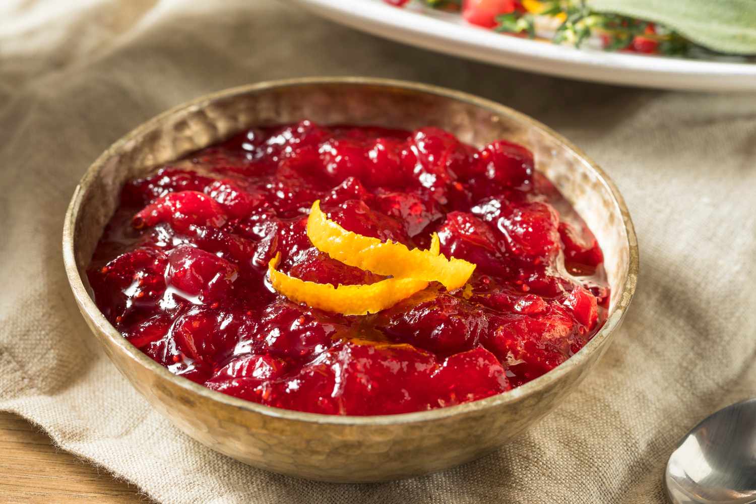 Angled view of a brown bowl of cranberry sauce on a brown table napkin