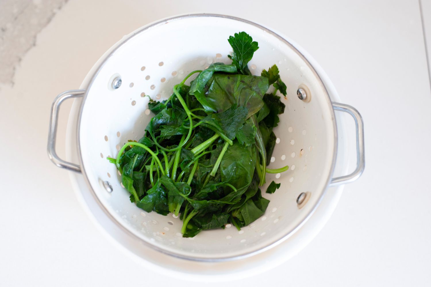 Herbs being drained in colander for scallion pesto