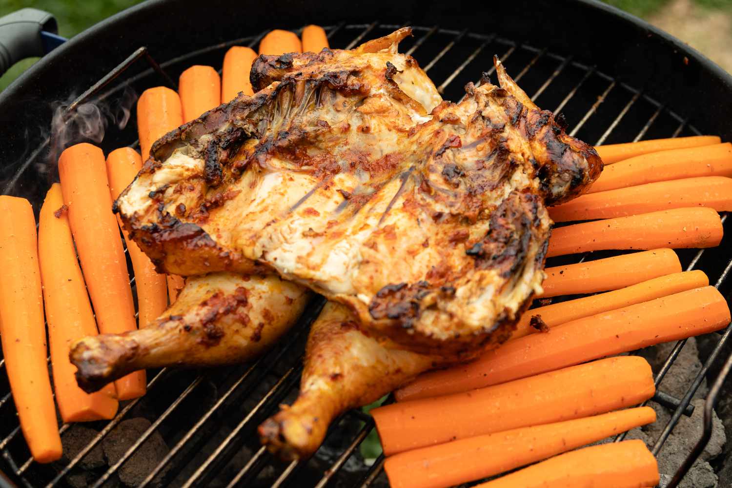 Smoked Spatchcock Chicken with Harissa Butter and Grilled Carrots on Grill