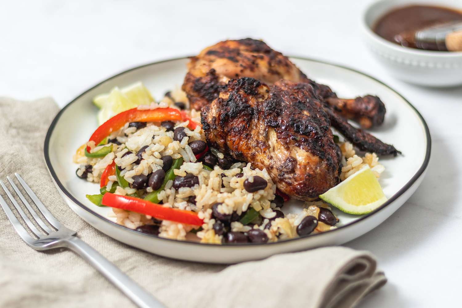 A plate of caribbean jerk served with beans and rice.