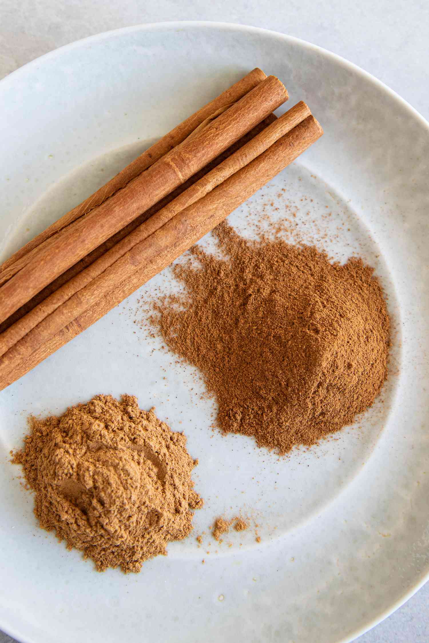 Cinnamon sticks and ground cinnamon on a white plate
