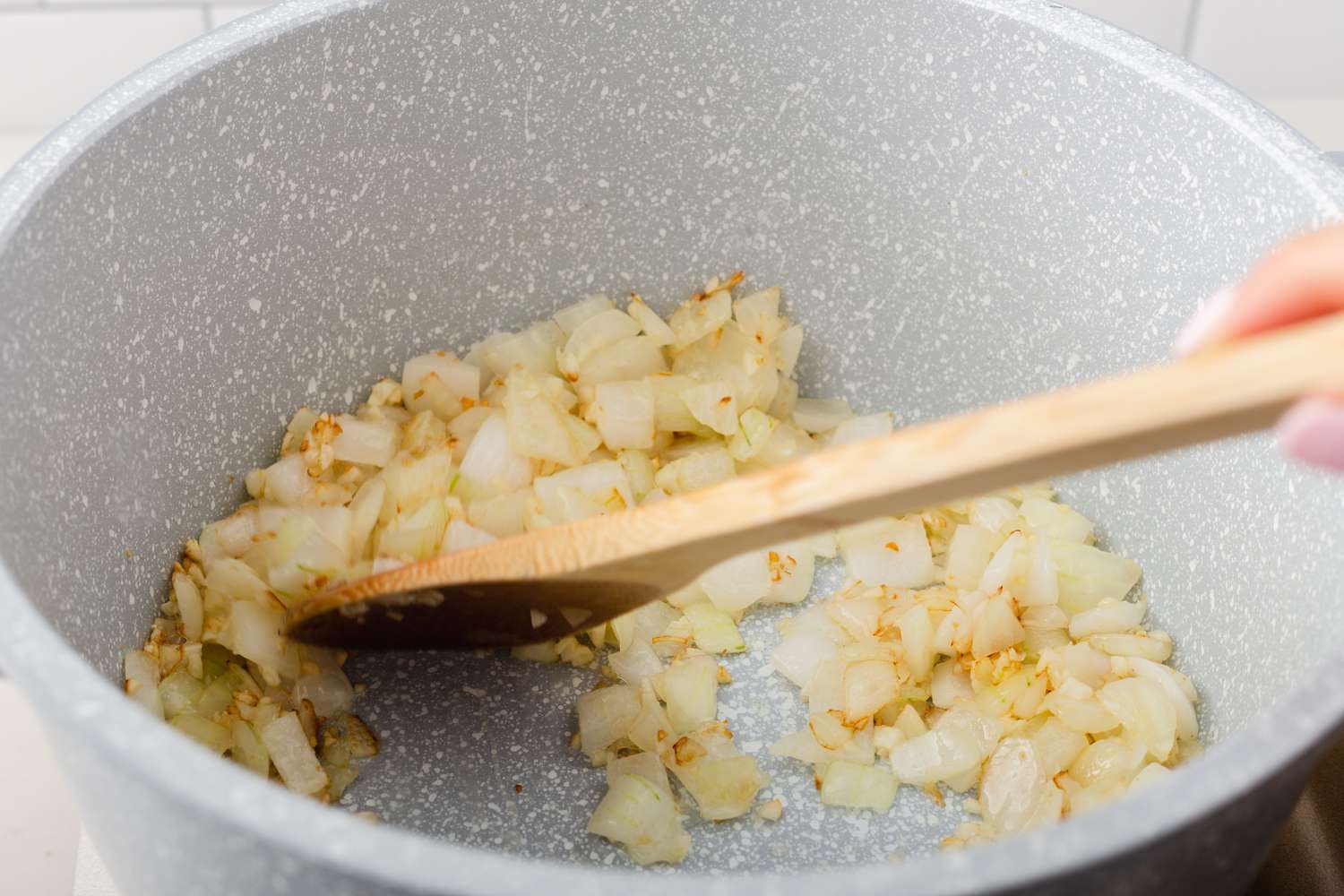 Stirring ingredients for a cowboy beans recipe with a wooden spoon.