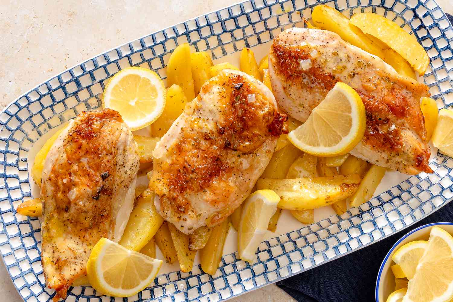 Greek-Style Lemon Chicken and Potatoes on a platter garnished with lemons