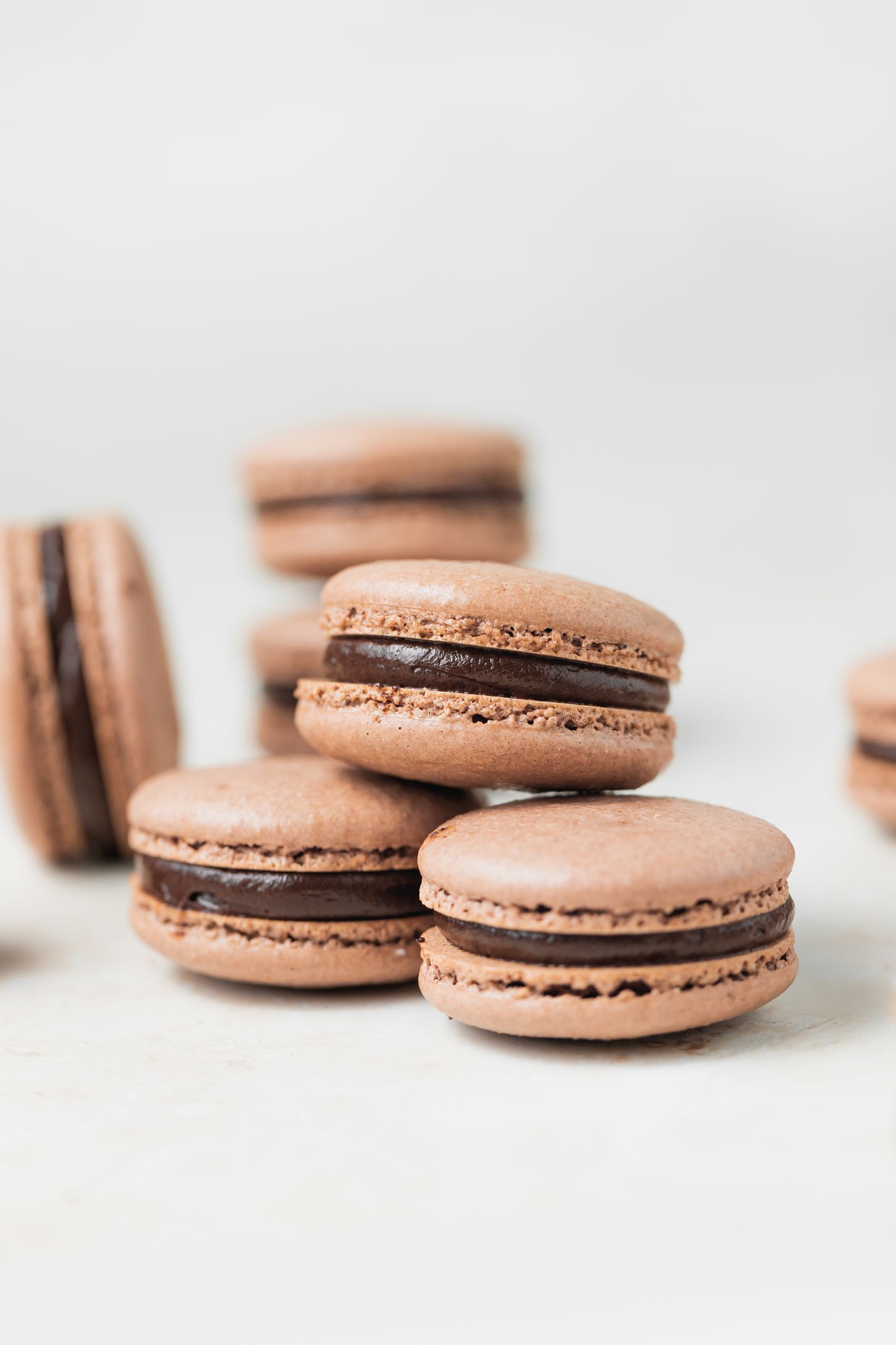 Side view of three chocolate macarons with dark chocolate ganache