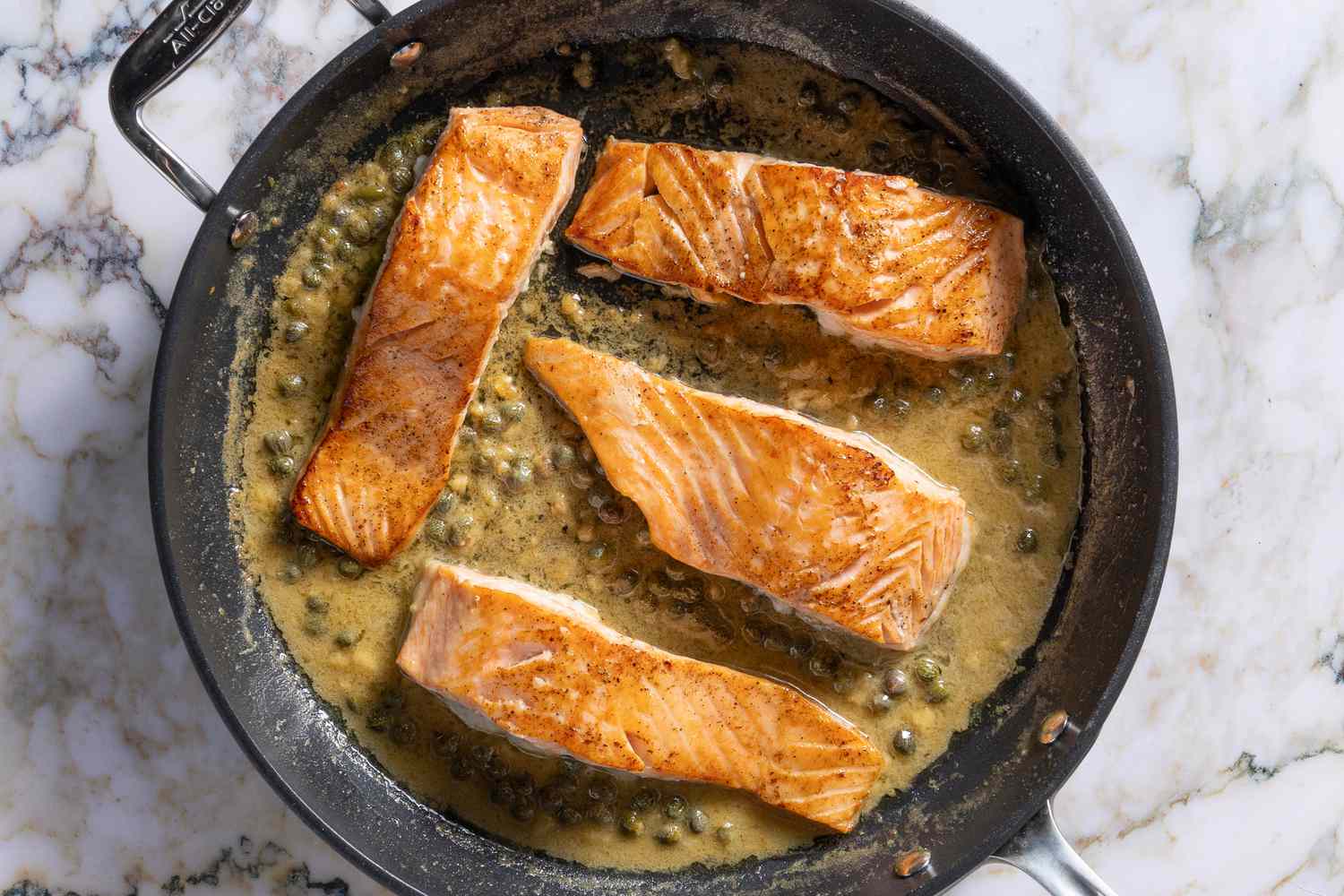 salmon fillets skin-side-down added to pan with sauce for Salmon Piccata