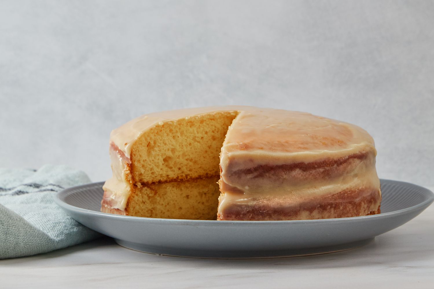 A layered cake with a slice removed resting on a plate for Reese Witherspoon's Sour Cream Cake