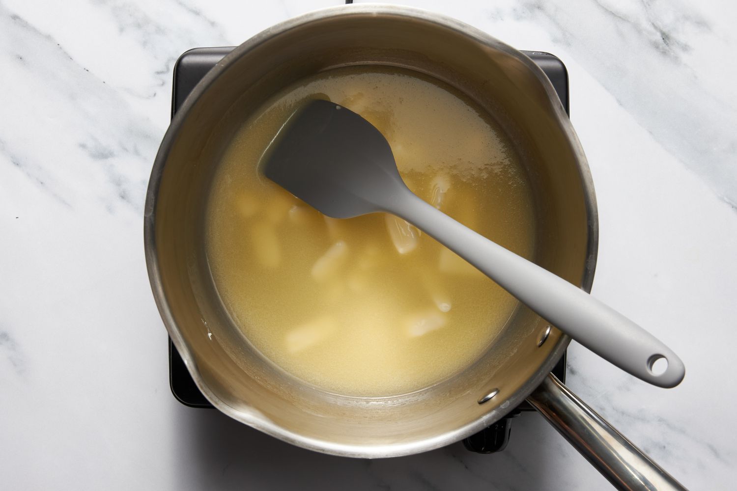 Butter melting in a sauce pan over a portable induction stove for bumpy cake recipe