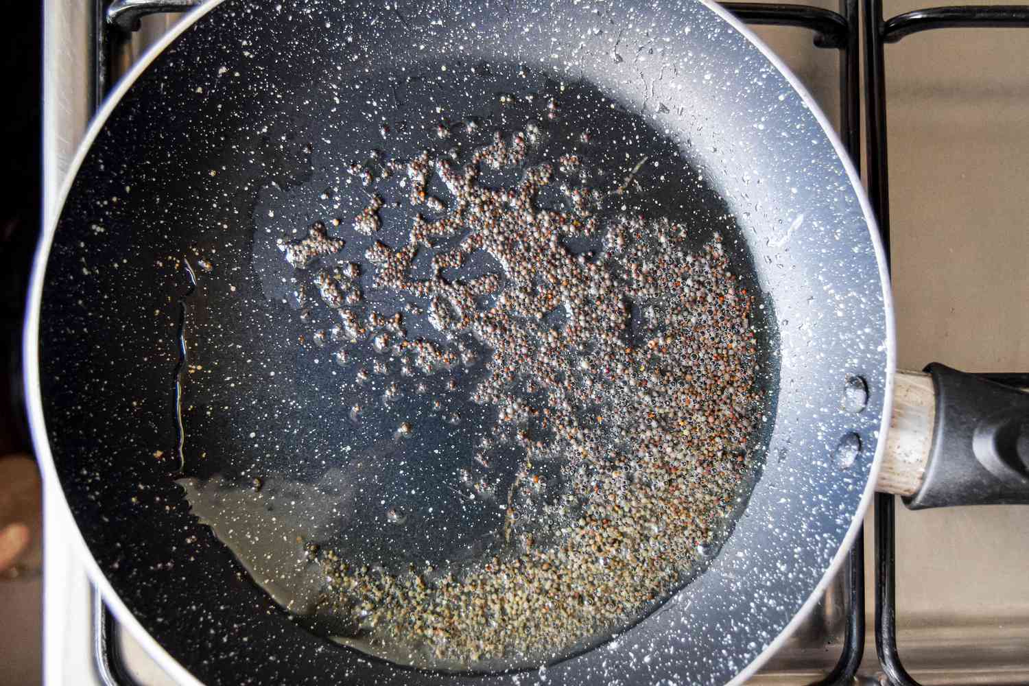 Mustard Seeds Blooming in a Skillet on the Stove with Melted Ghee for Egg Masala Curry Recipe